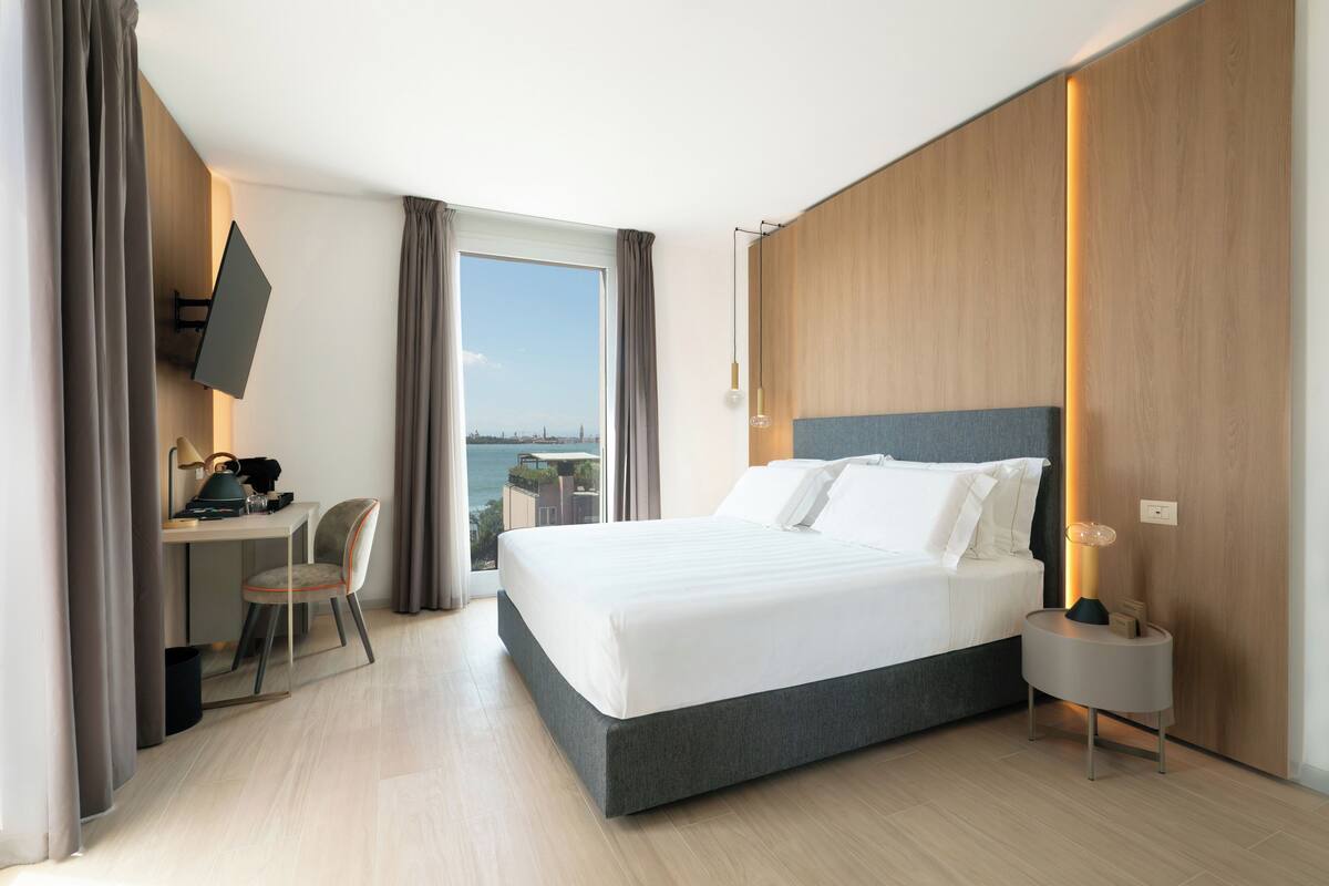 Une chambre d’hôtel moderne, dotée d’un grand lit, d’un bureau et d’une chaise.
