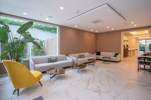 A modern living room with a sofa, armchair, coffee table, and a dining area with a chair and table. - Melia Venezia Lido (Venice)