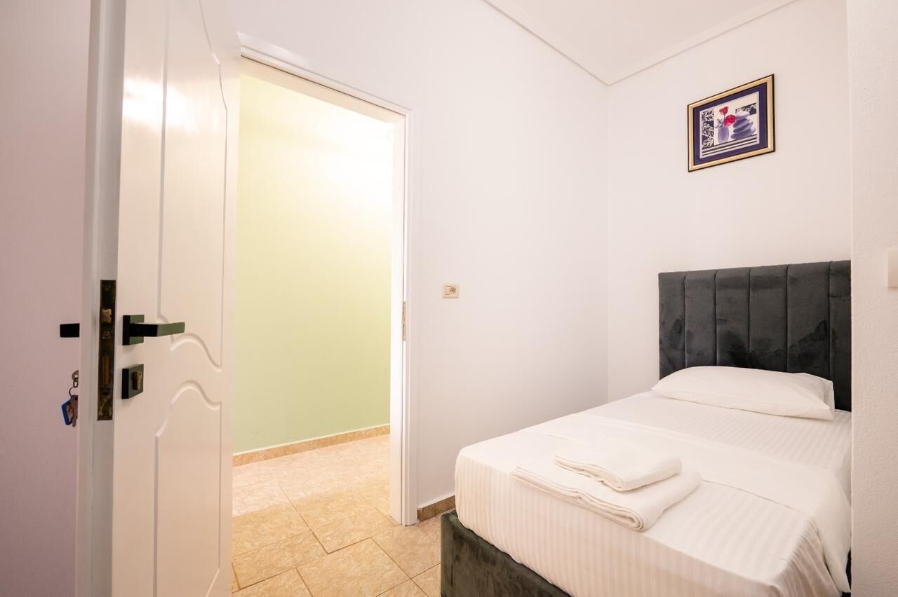 A hotel room with a bed, a door, and a framed picture on the wall.