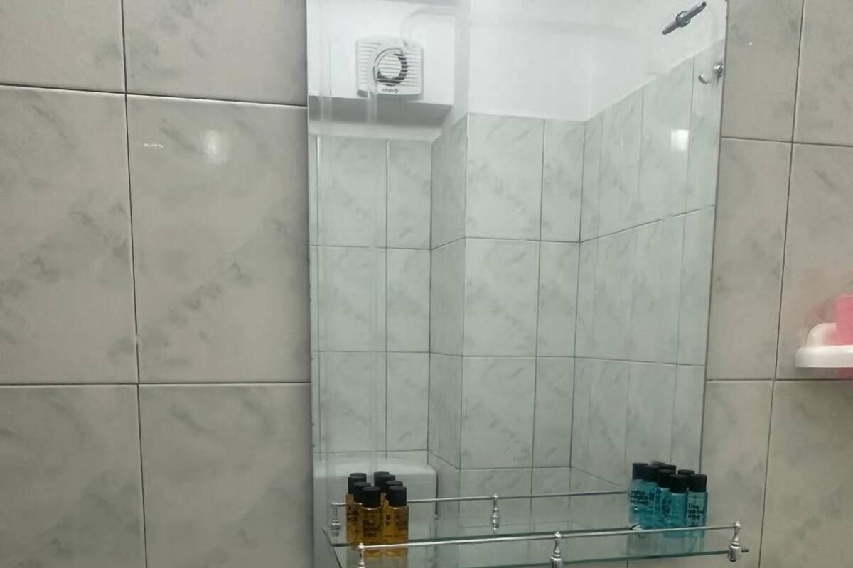 Ein Badezimmer mit einem weißen Waschbecken, einem Spiegel und einer Glasablage für Toilettenartikel.