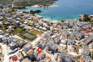 Vista aérea de un pueblo costero con viviendas densas, un espacio abierto central y una playa.