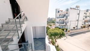 Un edifici modern amb una escala que condueix a un pis superior, un balcó amb un arbre i vista d'edificis veïns.