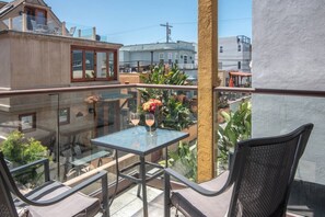 A balcony with a glass table, two chairs, and a vase with flowers. - The Beach House at Mission Bay (San Diego)