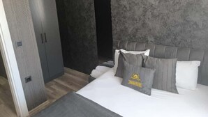 A bedroom with a bed, pillows, a wardrobe, and a textured wall. - Elite Residence PLUS (Izmir)