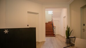 A reception area with a black desk, a staircase, and a potted plant.