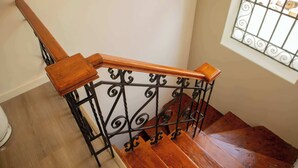 A wooden staircase with a metal railing and a window with decorative bars.