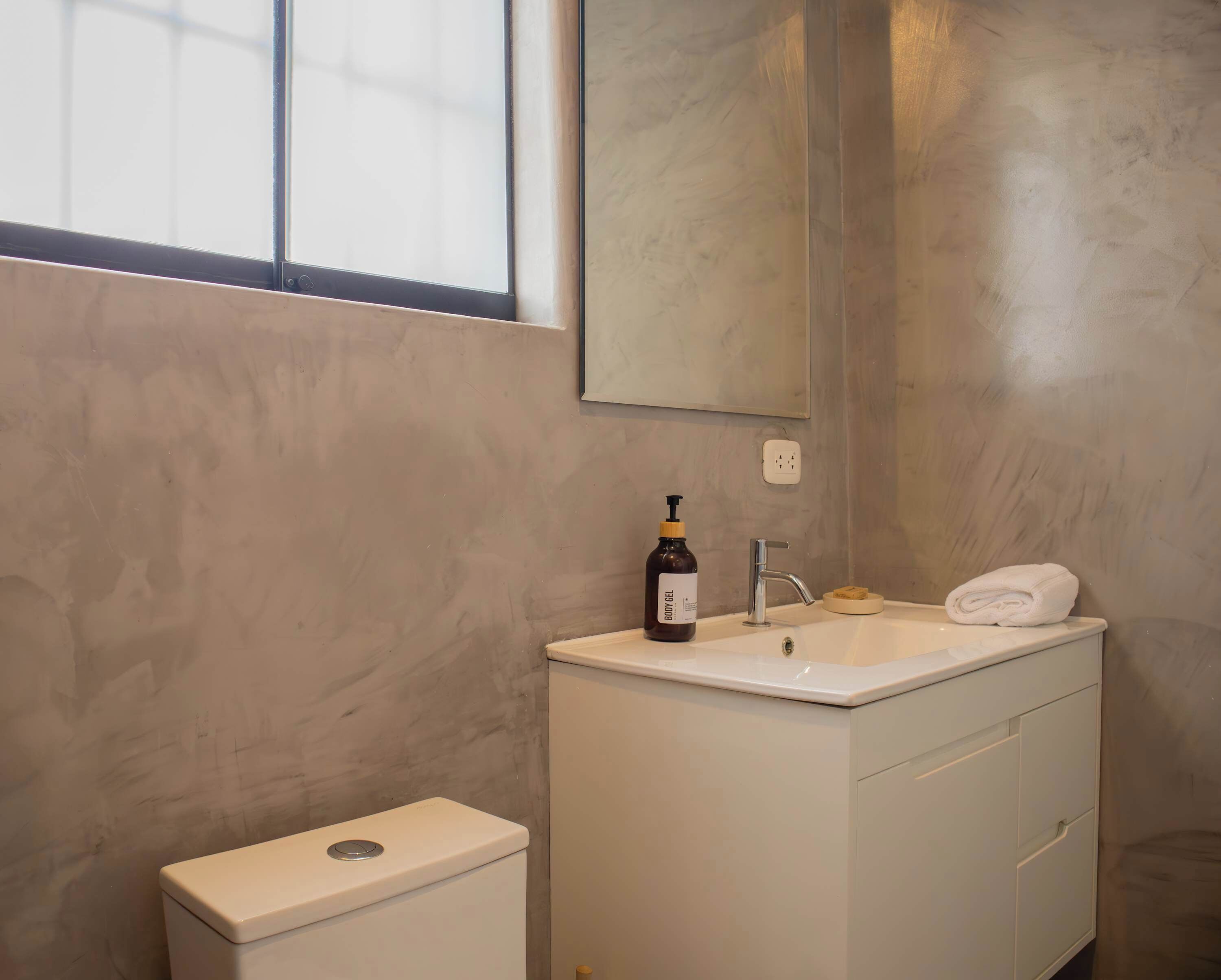 A bathroom with a white sink, a mirror, and a toilet.