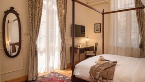 A four-poster bed with a wooden frame, a desk with a chair, a television, and a mirror on the wall. - Private fully serviced villa in Maadi, with a private pool, kitchen and garden. (Cairo Governorate)