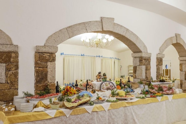 Una mesa de buffet con diversos alimentos y una araña en una habitación con paredes de piedra.