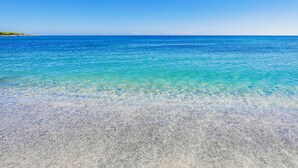 A clear view of a beach with shallow, turquoise water and a sandy shore. - Nicolaus Club Li Cucutti  (Agrustos)