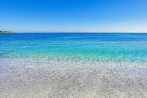 Una vista despejada de una playa con aguas turquesas poco profundas y una orilla arenosa.