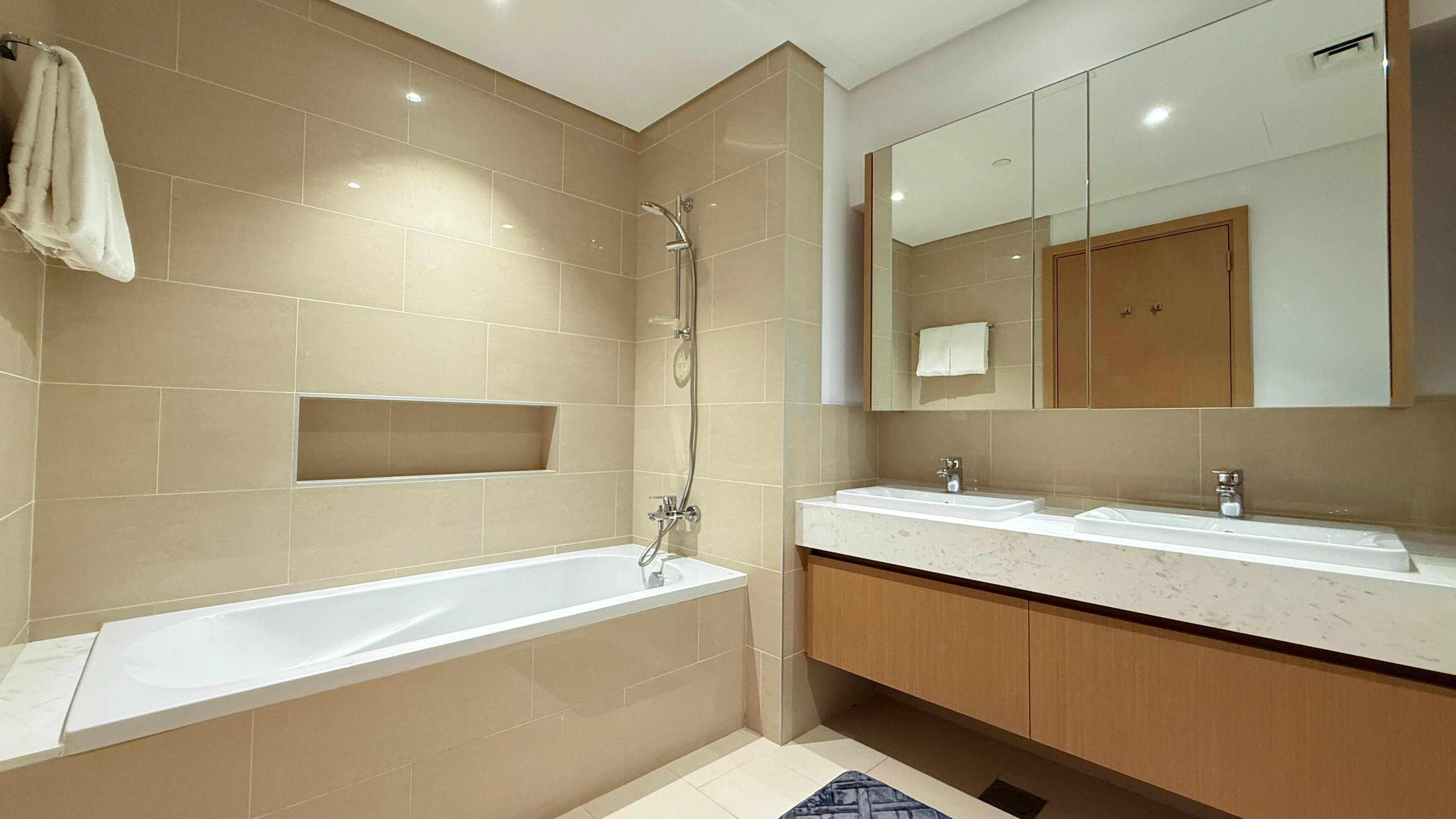 A modern bathroom with a bathtub, a shower, and a vanity with a mirror.
