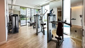 A spacious gym with various exercise equipment, large windows, and a wooden floor. - Dancenter Luxury 2 BR at Creek Side (Dubai)