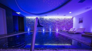 A spa area with a stone wall, a pool, and lounge chairs. - Nicolaus Prime Villas   (Castiadas)