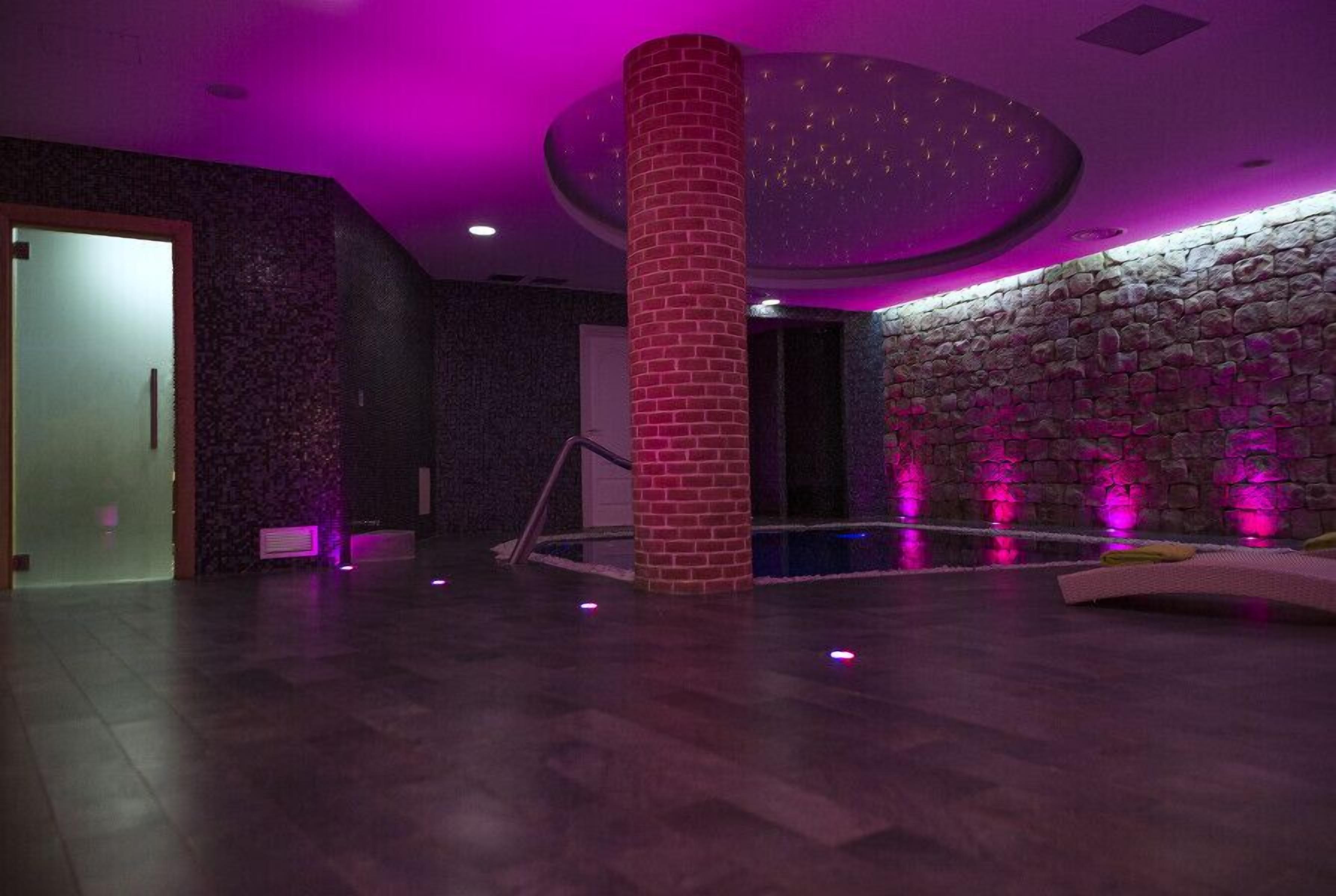 A spacious indoor area with a stone wall, a central pillar, and a ceiling with a circular light fixture.