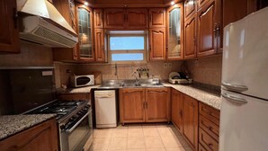 A kitchen with wooden cabinets, a microwave, a stove, a dishwasher, and a refrigerator. - Cozy 2-bedroom apartment in serene Cairo (Cairo Governorate)
