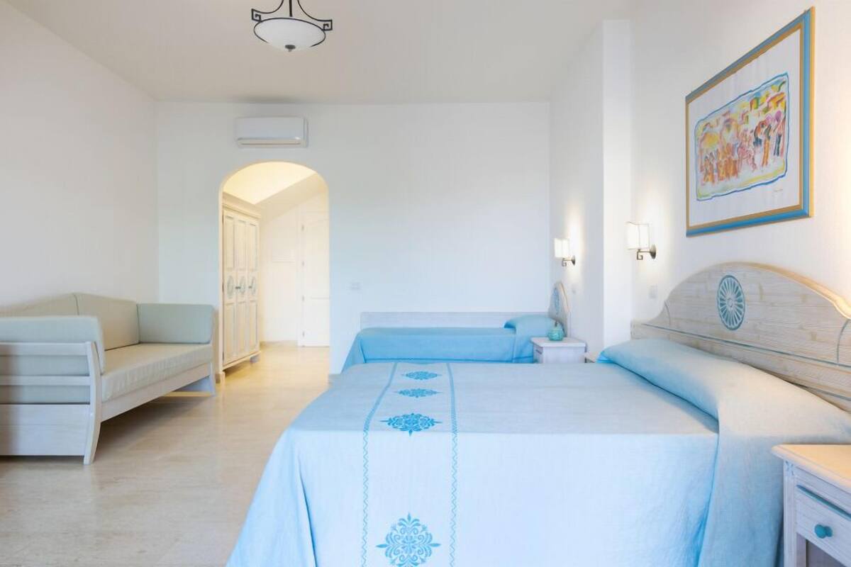 A bedroom with a bed, a nightstand, a lamp, and a painting on the wall.