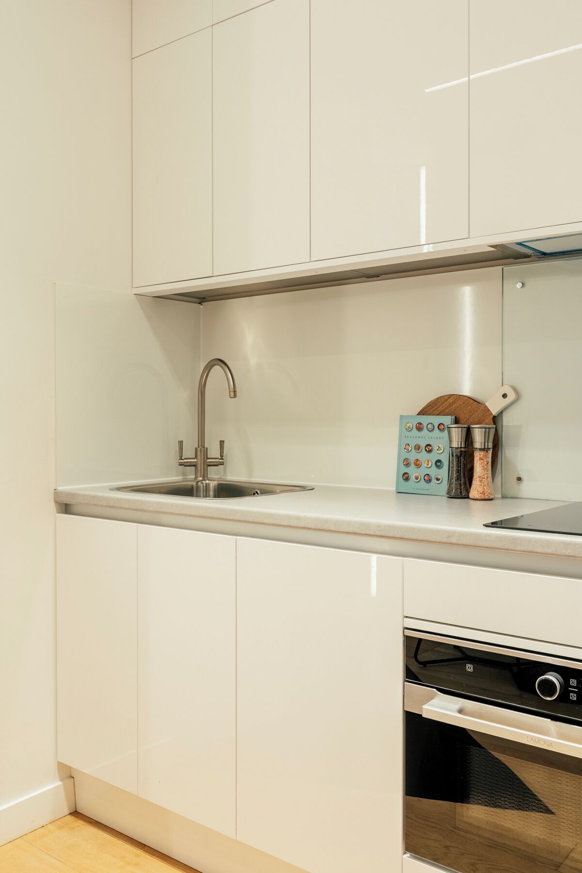 Una cocina con un lavamanos de acero inoxidable, un horno empotrado y un estante para especias.