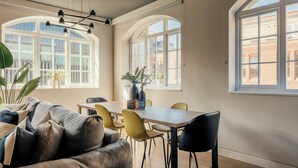 Un comedor con una mesa y sillas, ventanas amplias y una planta.