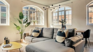 Una sala moderna con un sofá modular, ventanas amplias y un diseño minimalista.