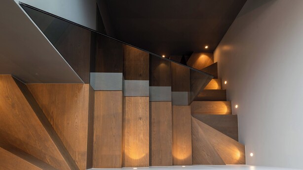 Una escalera moderna con paneles de madera y barandillas de vidrio.