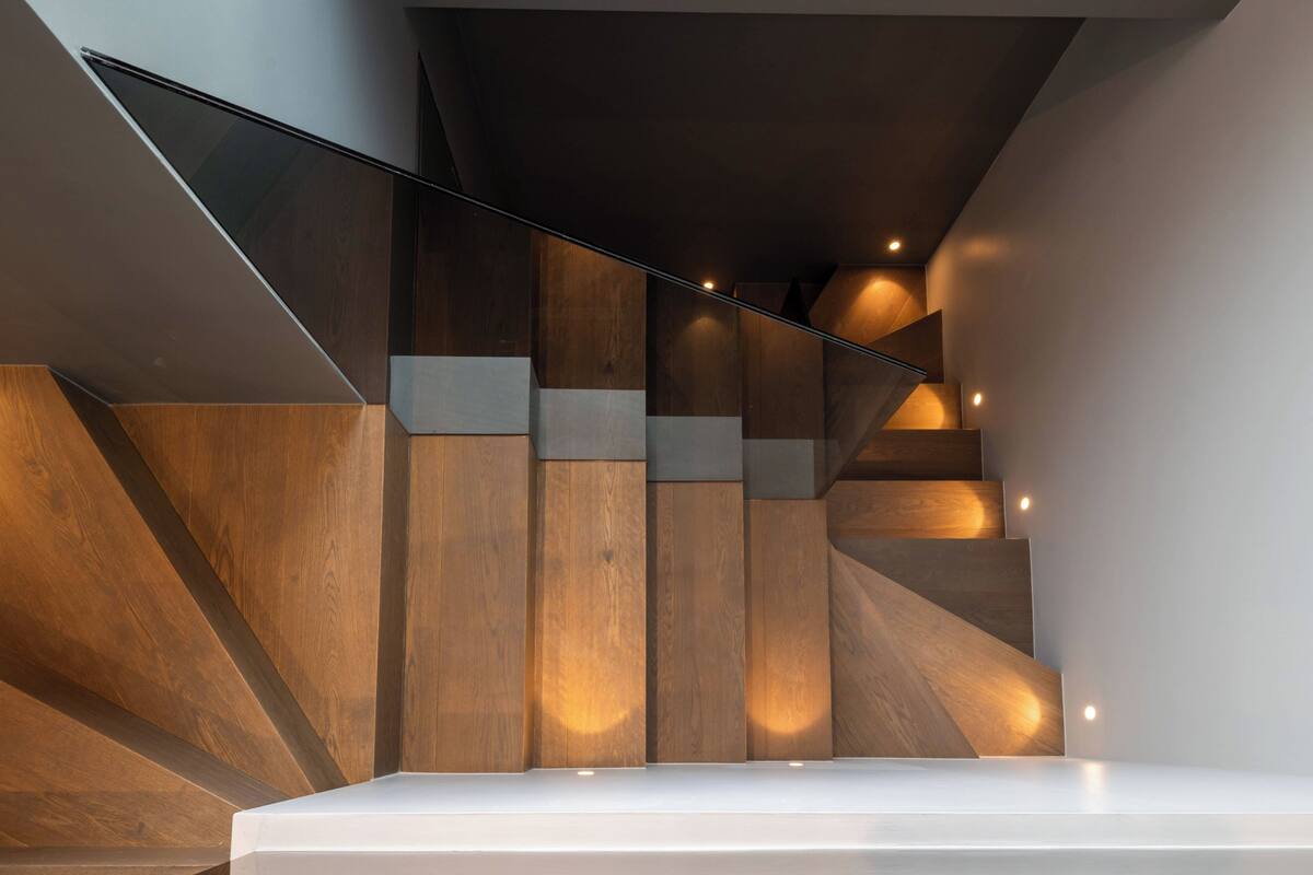 A modern staircase with wooden panels and glass railings.