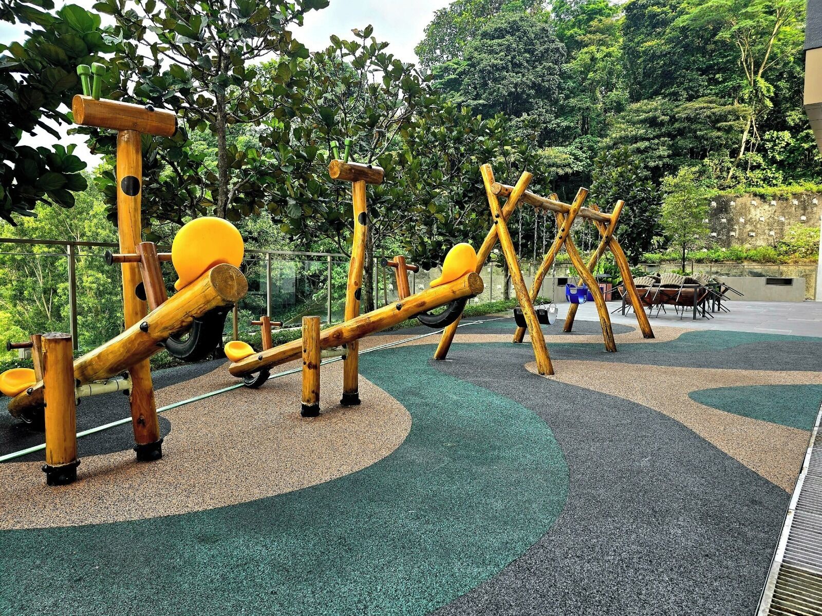 Un patio de juegos al aire libre con estructuras de madera y superficie de caucho verde.