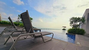A rooftop pool area with lounge chairs and a view of the sea. - Damansara Seresta (Batu Caves)