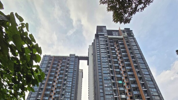 A high-rise residential building with multiple balconies, large windows, and a central reflective water feature. - Damansara Seresta (Batu Caves)