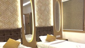 A hotel room with two beds, a large mirror, and a modern design. - Uptown Inn (Bengaluru)
