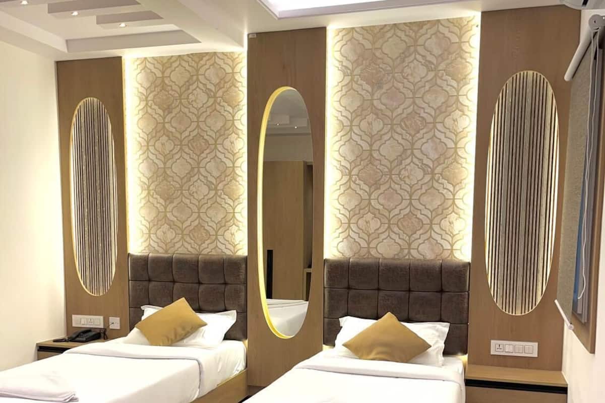 A modern hotel room with two beds, a large mirror, and patterned wallpaper.
