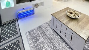 Ein modernes Wohnzimmer mit Flachbildfernseher, Einbauschränken, einer Küchenzeile und einem gemusterten Teppich.