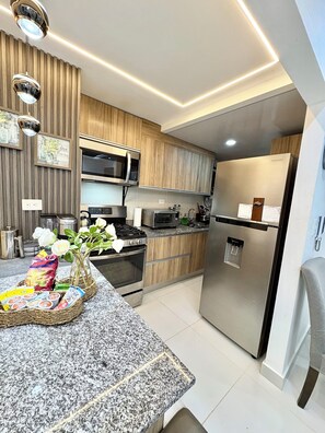 A modern kitchen with wooden cabinets, stainless steel appliances, and a granite countertop.