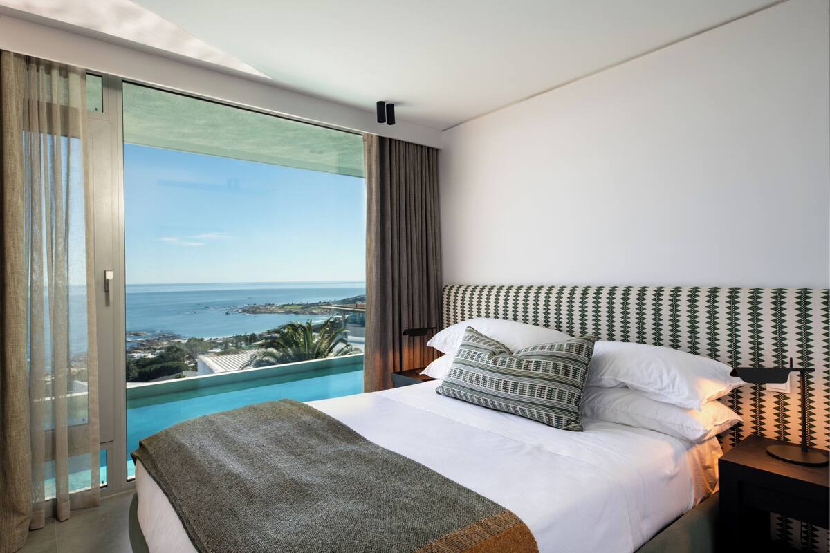 A hotel room with a large bed, a nightstand, and a view of the ocean.