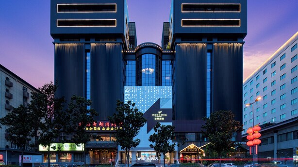 Een modern hotel met een symmetrische gevel, grote ramen en verlichte signage.