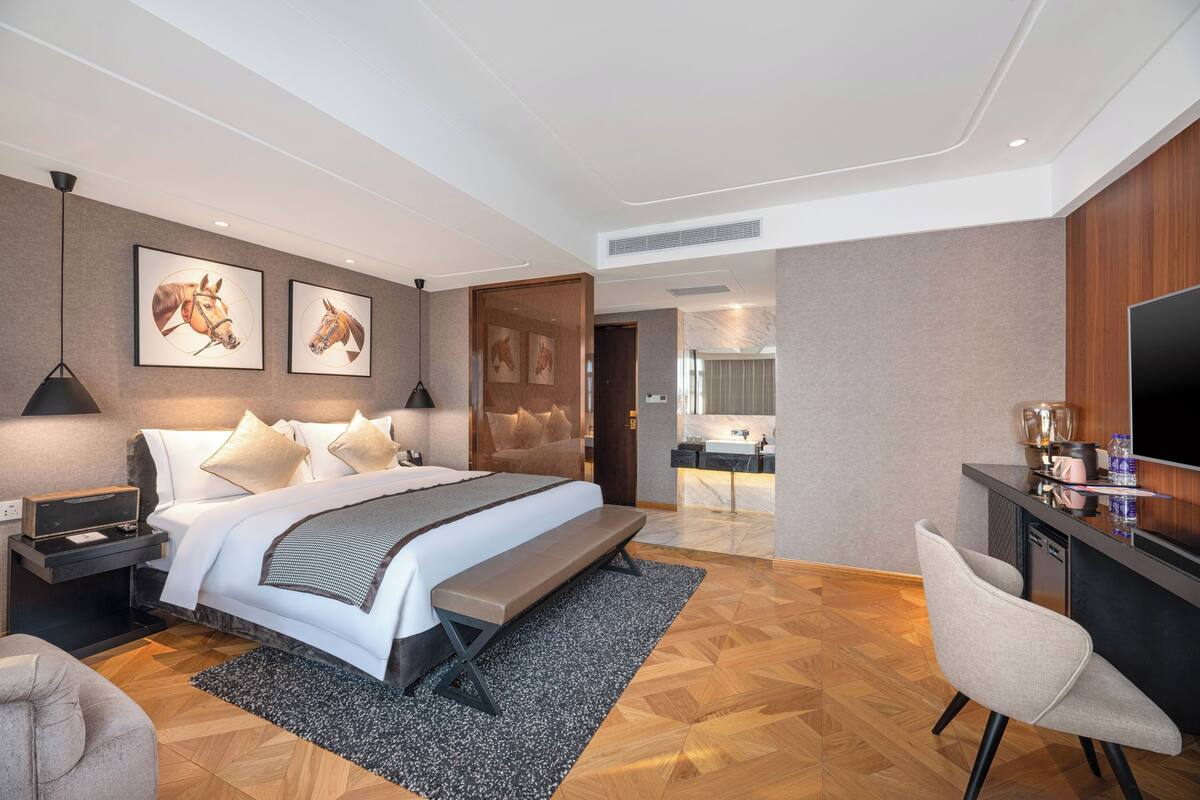 Una habitación de hotel moderna con una cama grande, un escritorio, una silla y obras de arte en las paredes.