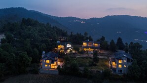 A residential area with multiple houses, surrounded by dense forest and hills. - Himvan by Akama Homes (Dhari)