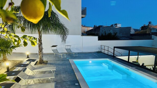 A rooftop pool area with lounge chairs and a palm tree. - Suite Costa Sicana (Siculiana)