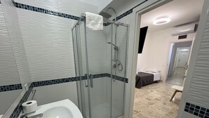 A modern bathroom with a glass-enclosed shower, a white sink with a soap dispenser, and a toilet. - Suite Costa Sicana (Siculiana)