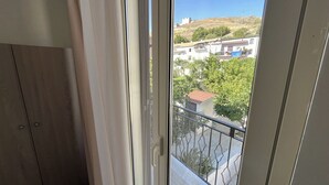 A balcony with a metal railing, a view of a residential area with houses and trees, and a clear sky. - Suite Costa Sicana (Siculiana)
