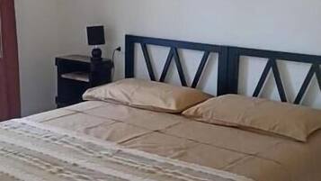 Un lit avec une couvre-lit à rayures, une tête de lit en bois et une table de chevet avec une lampe.