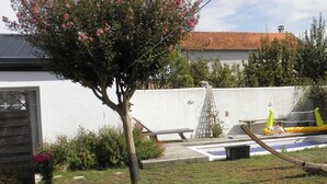 Ein Wohngebiet mit einem weißen Gebäude, einem Baum mit rosa Blüten, einer Leiter und einem gelben Gegenstand.