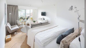 Une chambre d’hôtel moderne, dotée d’un grand lit, d’un bureau, d’une chaise et offrant une vue sur l’extérieur.