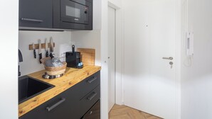 Une cuisine compacte équipée d’un four à micro-ondes, d’un ensemble de couteaux et d’une planche à découper en bois.