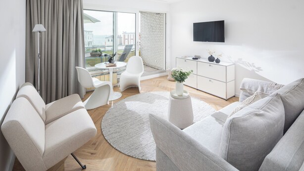 Un salon moderne avec un canapé, des fauteuils, une table basse et un téléviseur.