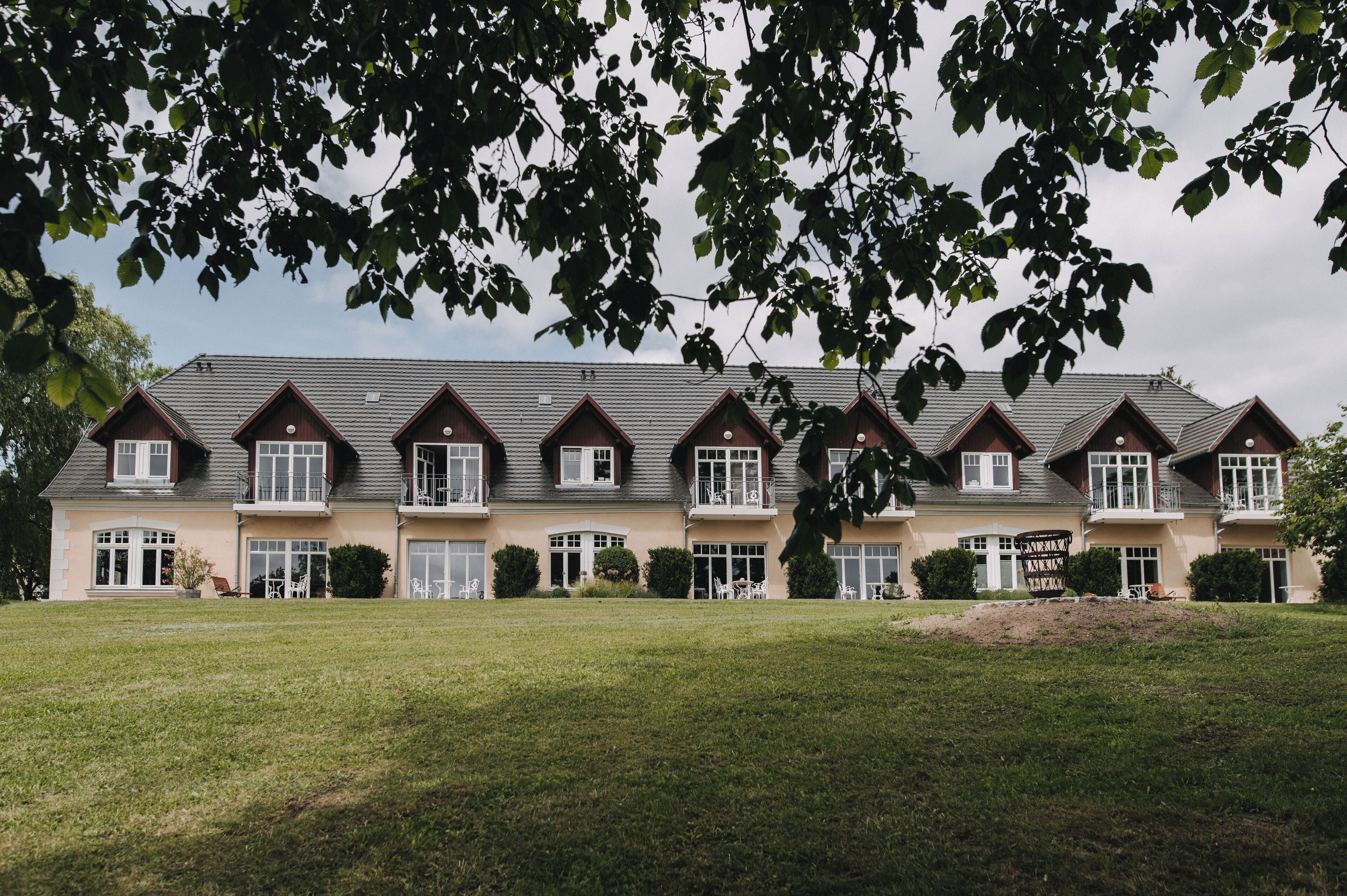 A large, multi-story building with a symmetrical facade, multiple balconies, and a well-maintained lawn.