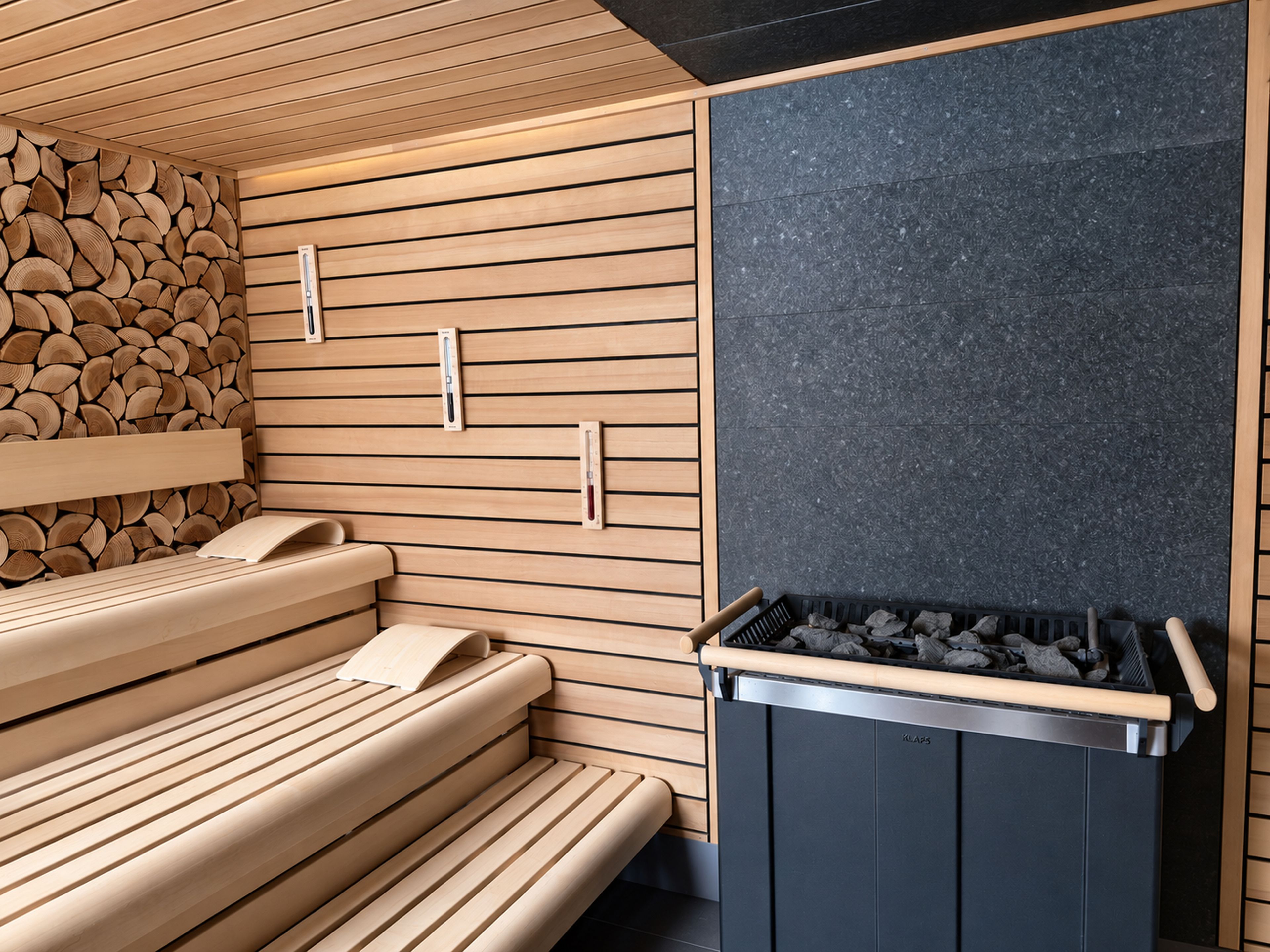 A sauna room with wooden benches and a stone wall.