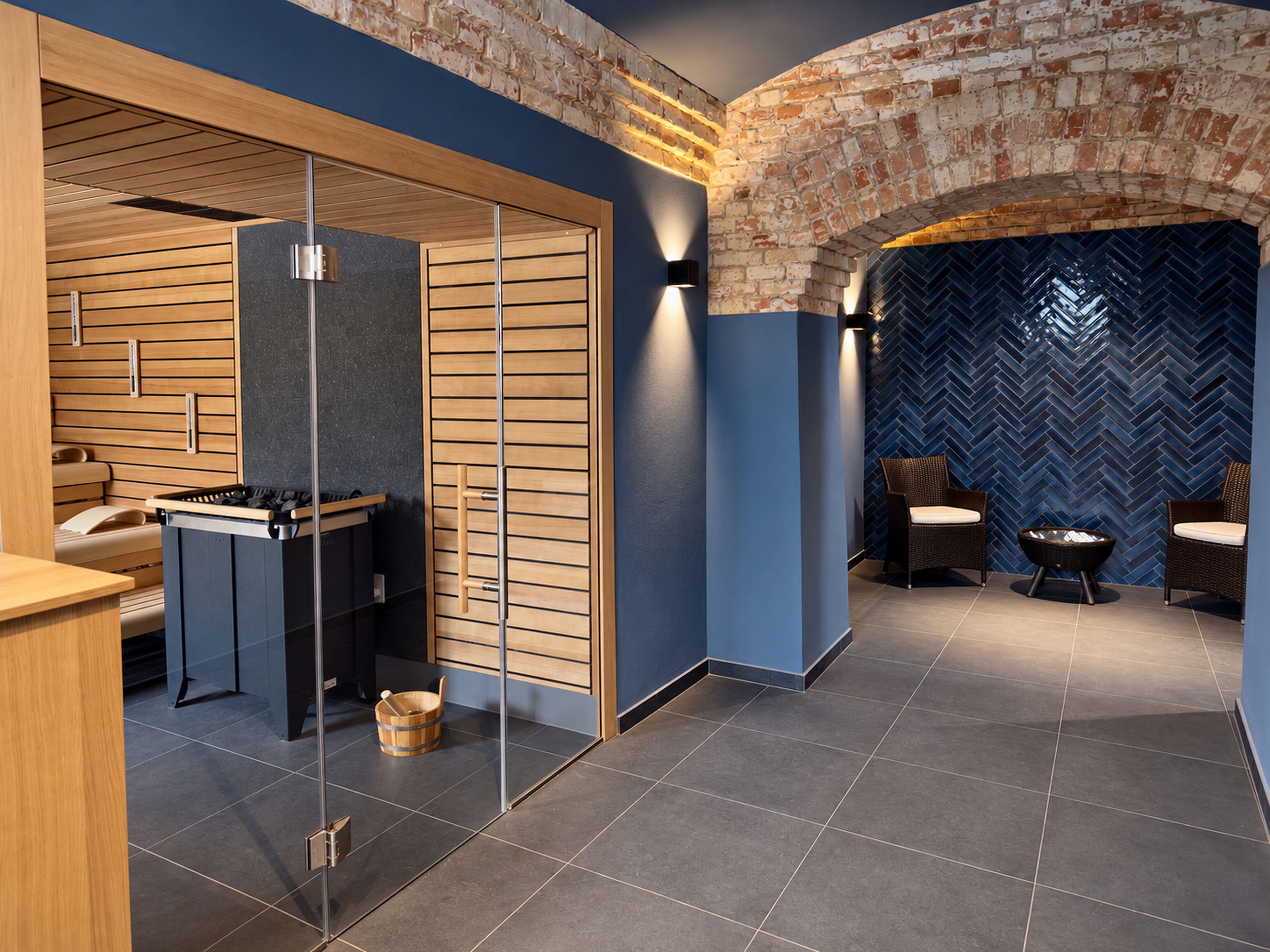 Un área de spa moderna con sauna de madera, camilla de masaje y zona de estar con mobiliario de mimbre.