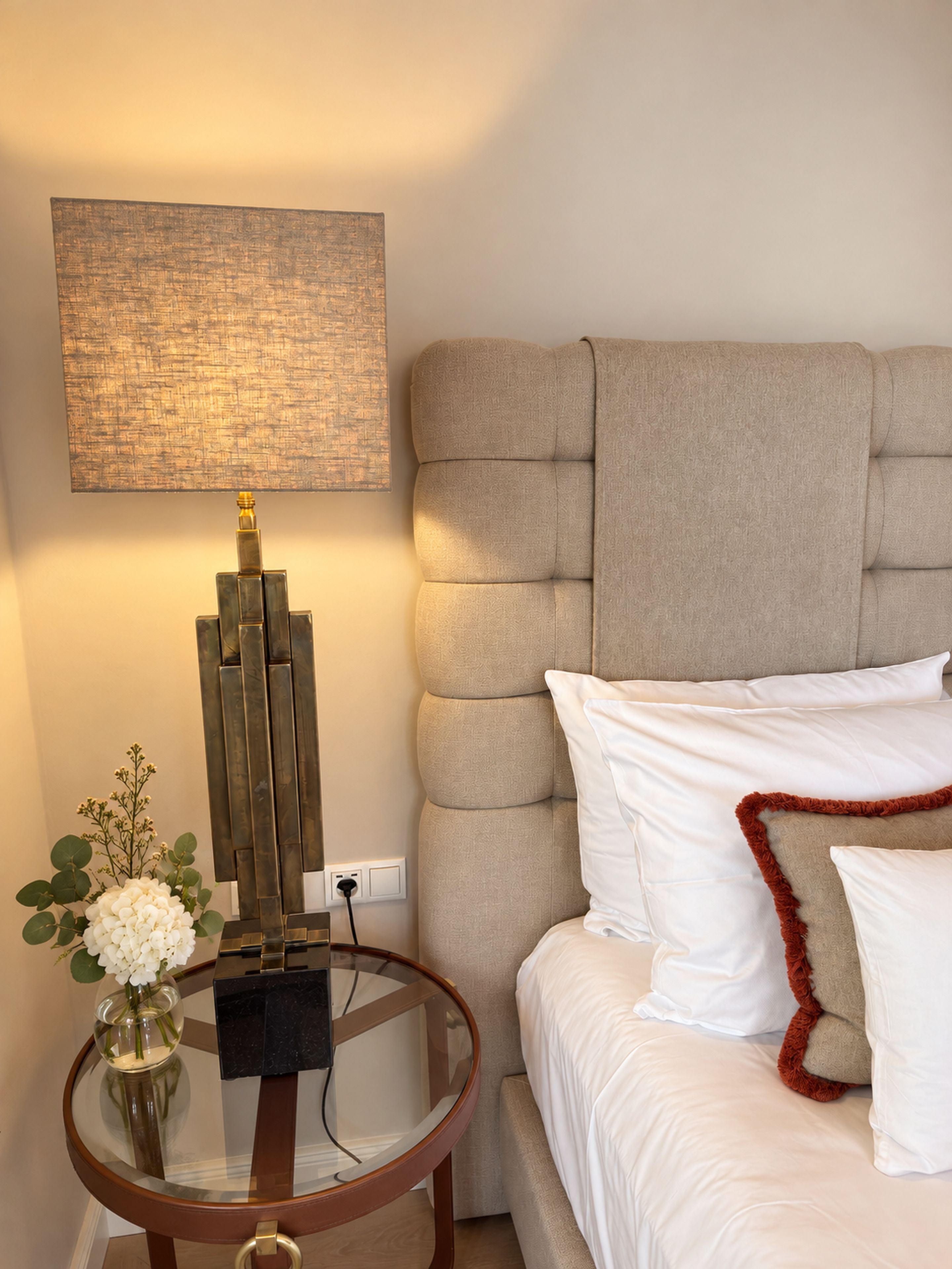 A bedroom with a bed, a bedside table with a lamp, and a wall-mounted artwork.