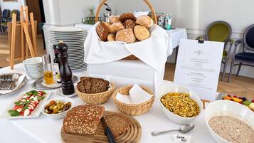 A buffet table with various food items, including bread, salads, and a bowl of granola.